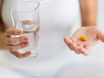 Женщина держит в руках таблетку и стакан с водой